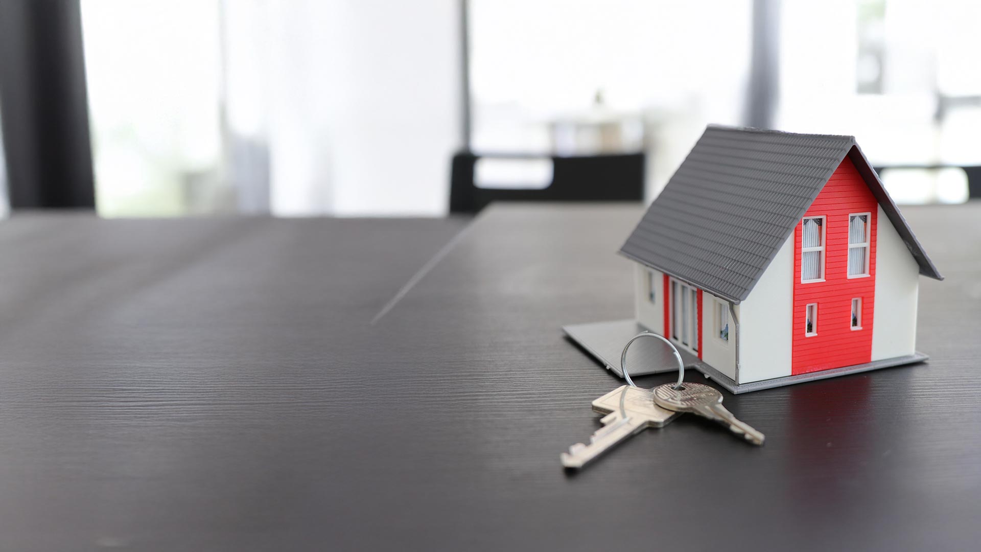 Modellhaus mit Schlüsseln auf einem Tisch – Hinweise zum Glasfaseranschluss für Hauseigentümer im Netz von Wettingen4net in Wettingen